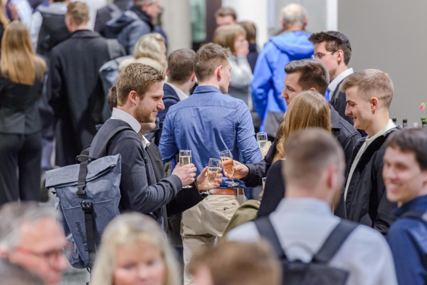 Ehemalige Studierende stoßen mit Sekt an