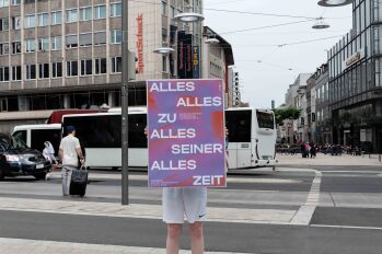 Eine Person hält ein Plakat hoch und steht auf einer Straßenkreuzung