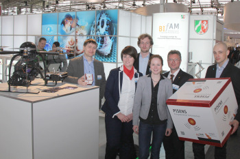 Gruppenfoto des Instituts Bielefelder Institut für Angewandte Materialforschung kurz BIfAM auf dem eigenen Messestand, neben der ausgestellten Drohne