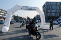 Motorrad beim Start mit einem Mann der eine Fahne schwengt.