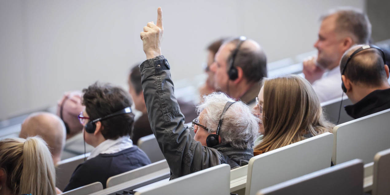 Eine person im Audimax aus dem Publikum meldet sich