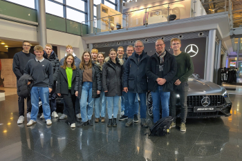 Eine Gruppe Personen steht vor einem Mercedes-Auto