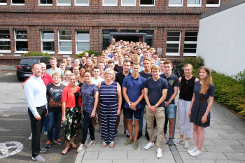 Gruppe von rund 90 Menschen steht vor dem Flöttmanngebäude in Gütersloh.