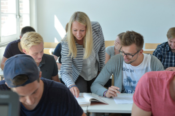 Eine Frau zeigt in einem aufgeschlagenem Buch einem Studenten einen Text