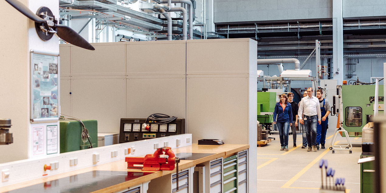 Mehrere Studierende und ein Professor laufen durch die Experimentierhalle der FH Bielefeld