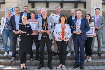 Gruppenfoto mit 13 Personen. Drei Personen halten den CSR Preis in den Händen.