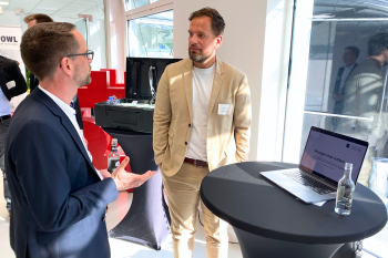 Dr. Andreas Hellmann spricht mit einem Besucher an einem Stehtisch.