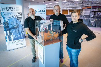 Gruppenbild des Da Vinci@HSBI Teams am Ort der Ausstellung in der neuen Wissenswerkstadt Von links nach rechts stehen ein schwarzen T Shirts oder Pullovern Andreas Wollensak, Marc Oliver Schierenberg, Andreas Born um eine Vitrine herum