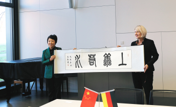 Zwei Personen halt ein Banner mit chinesischen Schriftzeichen.