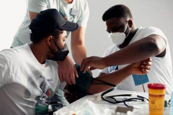 Ein Student legt bei einem anderen Studenten ein Blutdruckmessgerät an.