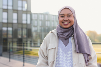 Putri Jumadi steht vor dem Eingang der Tiefgarage und lächelt in die Kamera