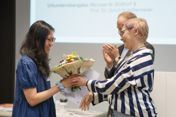 Hannah Möhring übergibt einen Blumenstrauß an Thuy Linh Pham