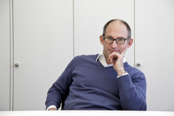 Porträtfoto von Prof. Dr.-Ing. Michael Eisfeld sitzend am Schreibtisch mit abgestütztem Arm am Gesicht.