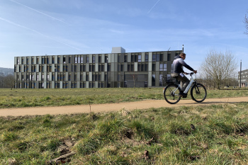 Ein Mann fährt auf einem Fahrrad vor dem Hauptgebäude der FH entlang