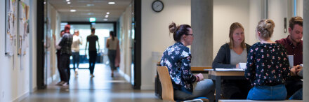 Eine Gruppe von Studierenden sitzt in einem Lernbereich in einem Gang in der FH zusammen und arbeitet