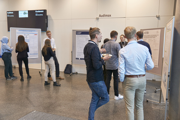 Nachwuchswissenschaftler diskutieren vor einer Posterausstellung