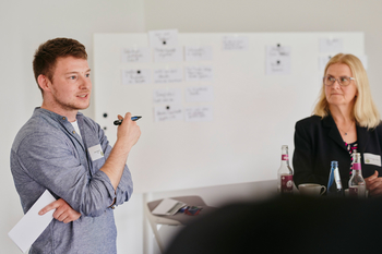 Zwei Personen diskutieren vor Whiteboard