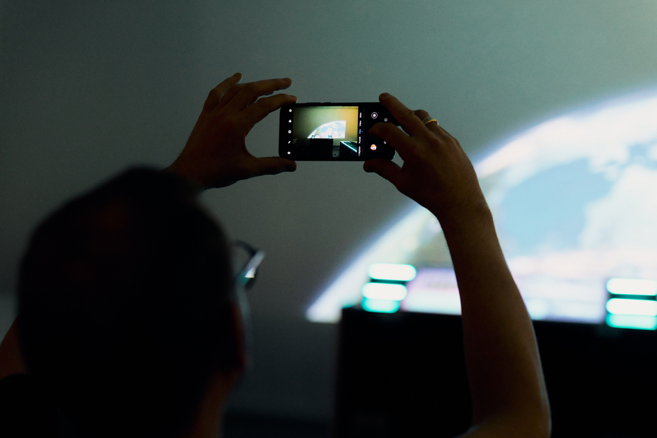 Eine Frau fotografiert mit einem handy die Weltraumshow der Wissenswerkstadt