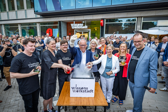 Personen vor der Tür der Wissenswerkstadt. Pit Clausen hält einen großen goldenen Schlüssel in die Luft