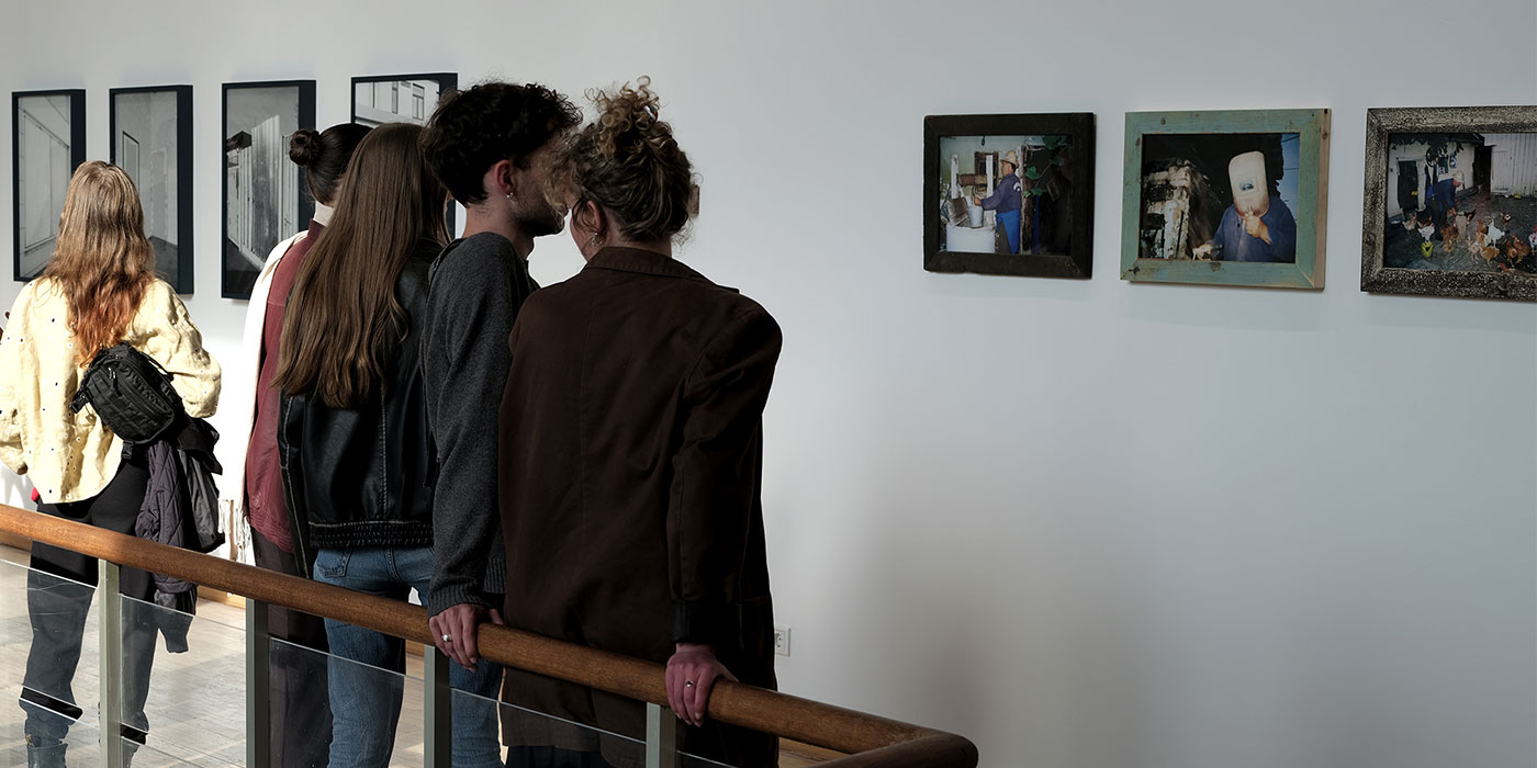 5 Personen stehen vor aufgehängten Fotos