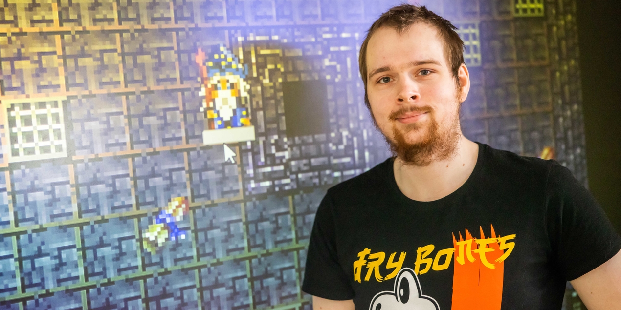 Ein Mann steht vor einer Wand auf die das Dungeon Spiel per Beamer projiziert wird