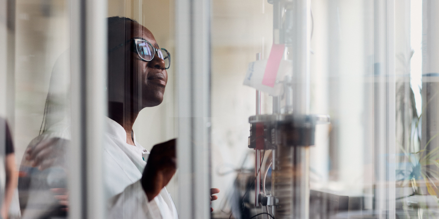 Nonsikelelo Sheron Mpofu im Textiltechnologie Labor der HSBI. Sie schaut auf ein Stück Stock im Zuggerät