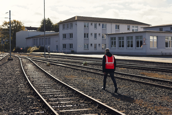 Ein Man in einer orangen Warnweste läuft über Bahngleise