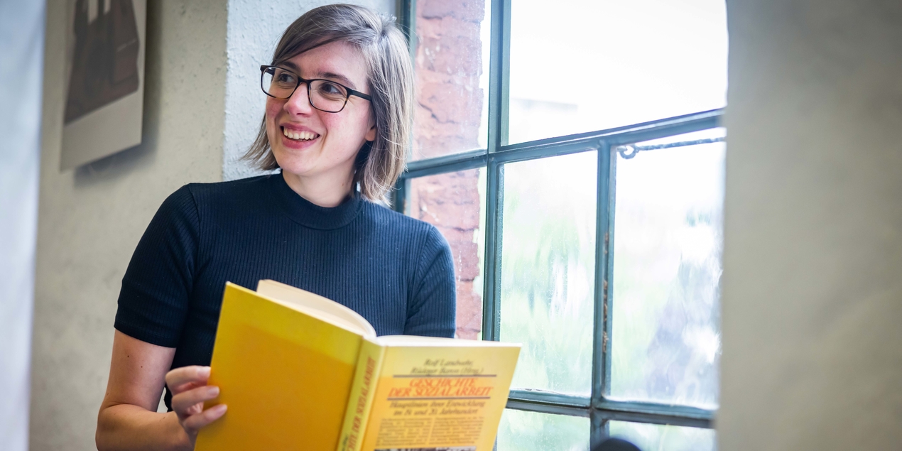 Sandra Holtgreve sitzt an einem Fenster und liest ein Buch