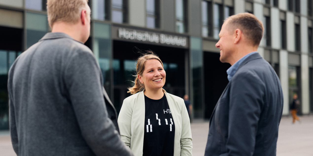 Drei Personen stehen vor der HSBI