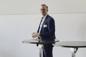 Eike Krull stands at a high table with moderation cards in his hand and gives a presentation