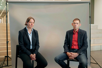 Prof. Dr. Änne Dörte-Latteck und Prof. Dr. Norbert Seidl sitzen vor einer grauen Leinwand