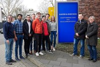 Eine Gruppe Menschen steht vor einem Schild mit der Aufschrift Haver & Boecker