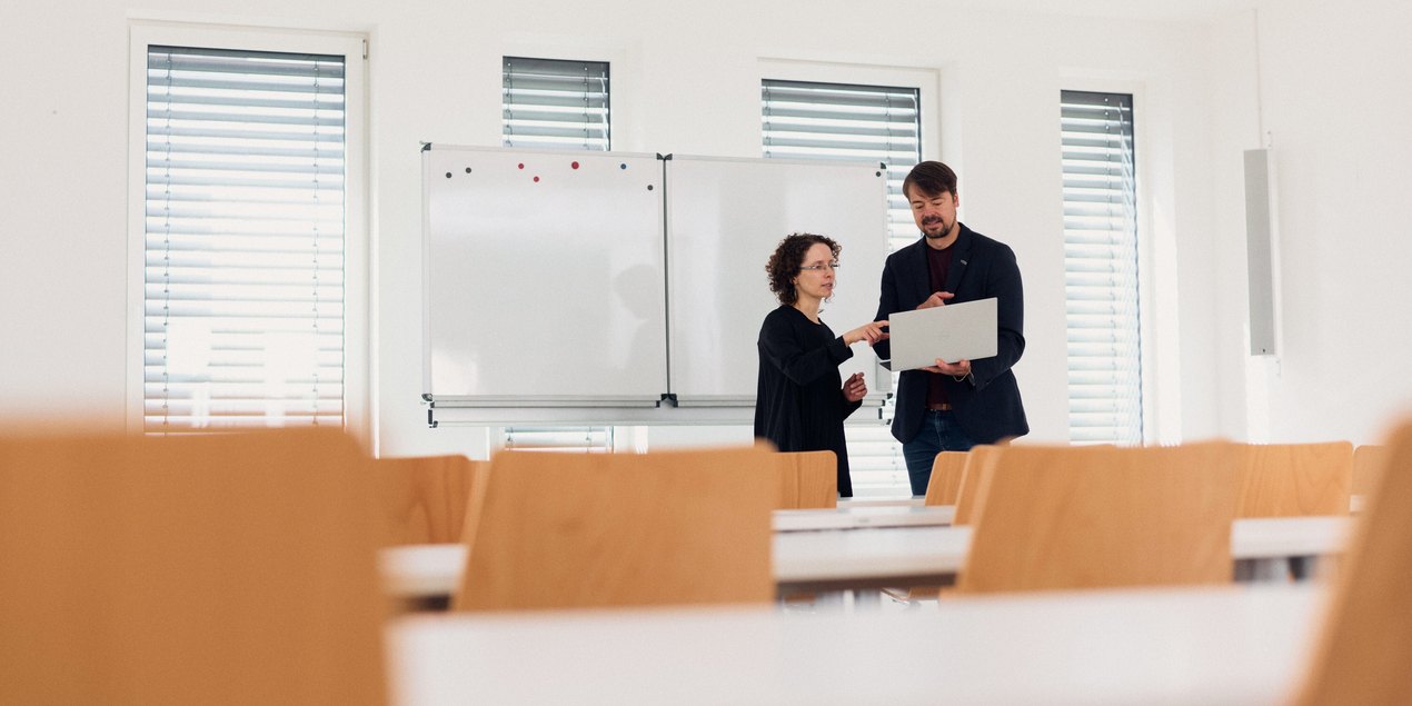 zwei Personen unterhalten sich in einem Seminarraum