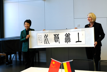 Zwei Personen halten ein Banner mit chinesischen Schriftzeichen in den Händen.