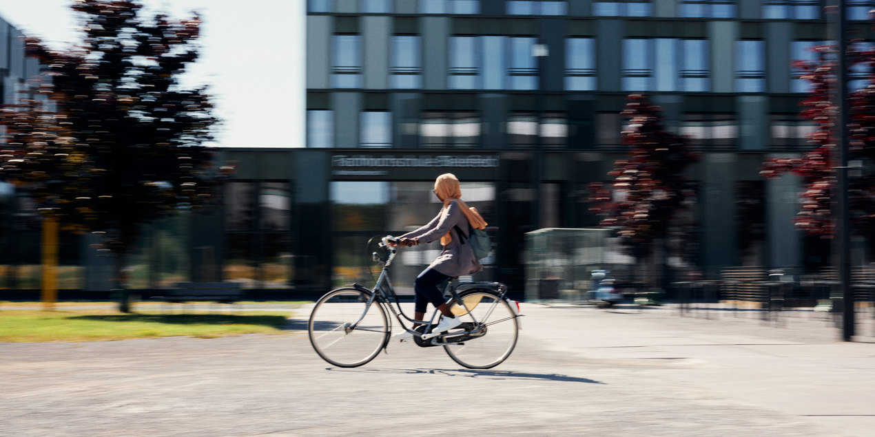 Hamdiya Alhassan fährt mit einem Fahrrad über den Campus der FH Bielefeld