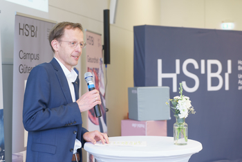Prof. Ulrich Schäfermeier hält ein Mikrofon in der Hand und begrüßt die Gäste