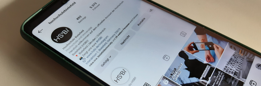 Auf einem Tisch liegt ein iPhone, auf dem der Instagram-Account der FH Bielefeld geöffnet ist.
