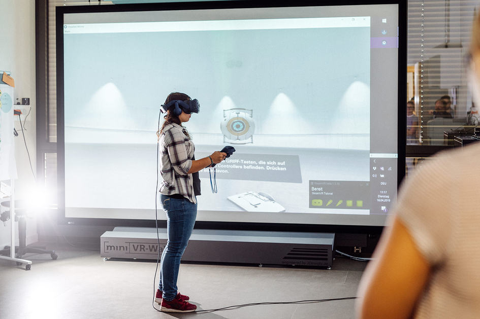 Eine Frau bewegt sich mit Hilfe einer VR-Brille im virtuellen Raum