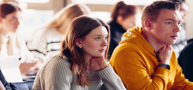 Eine Studentin sitzt am Tisch in einem Seminarraum